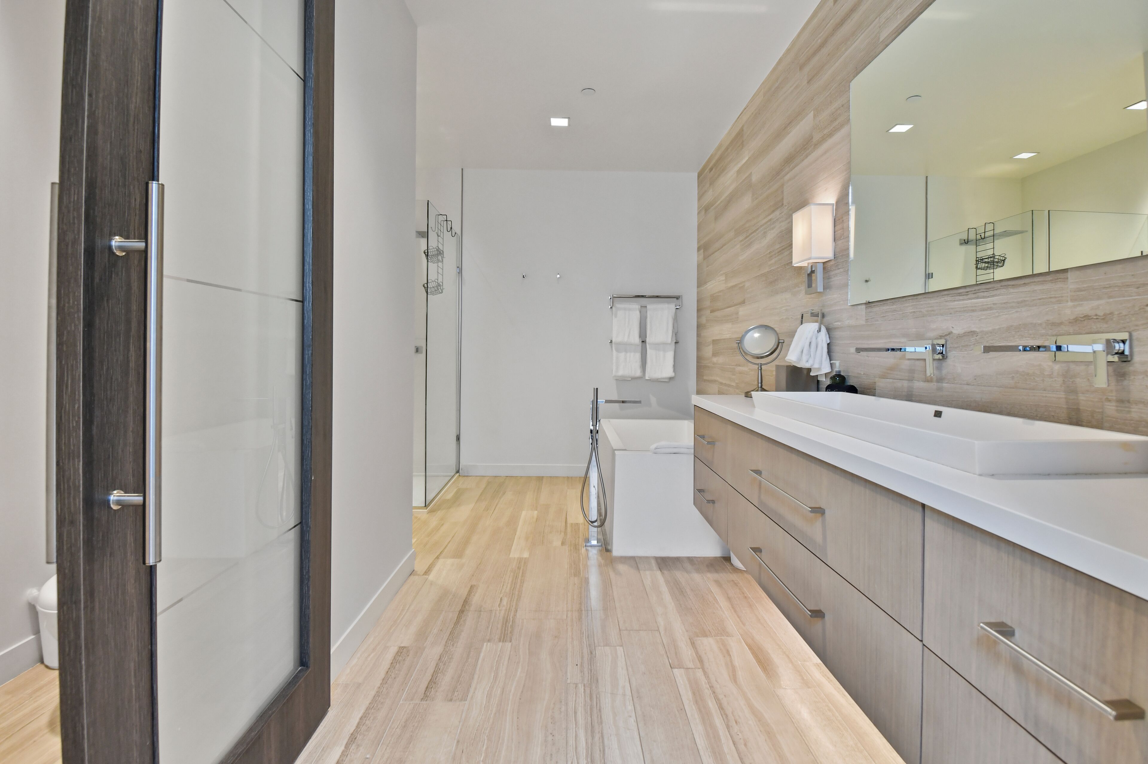 A modern bathroom with a large mirror, a bathtub, and a shower.