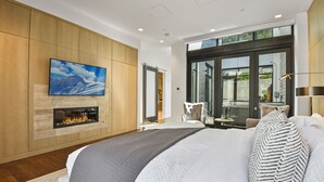 A modern bedroom with a large bed, a fireplace, a TV, and a view of the outdoors. - Parkite on Main (Park City)
