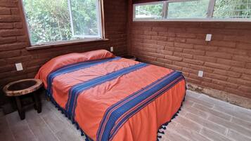 A room with a bed, a small stool, and a window.