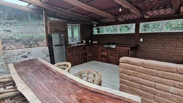 An outdoor kitchen area with a built-in counter, bar stools, and a brick wall.