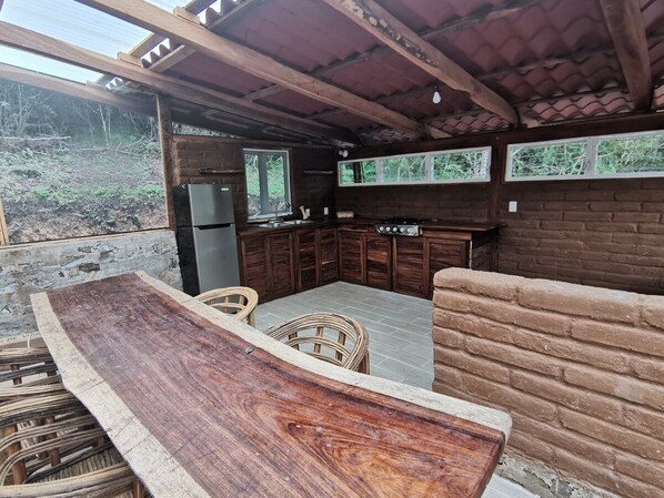 Un área de cocina al aire libre con mostrador integrado, taburetes de bar y pared de ladrillo.