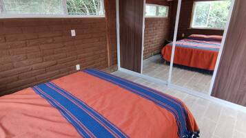 A bedroom with a large bed, a sliding glass door, and a view of the outdoors.