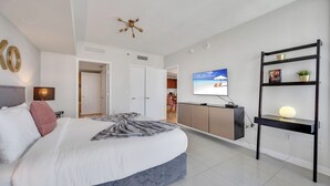 A modern bedroom with a large bed, a TV mounted on the wall, and a desk with a shelf. - Icon Luxury 34th Floor Amazing Oceanview, Brickell (Miami)