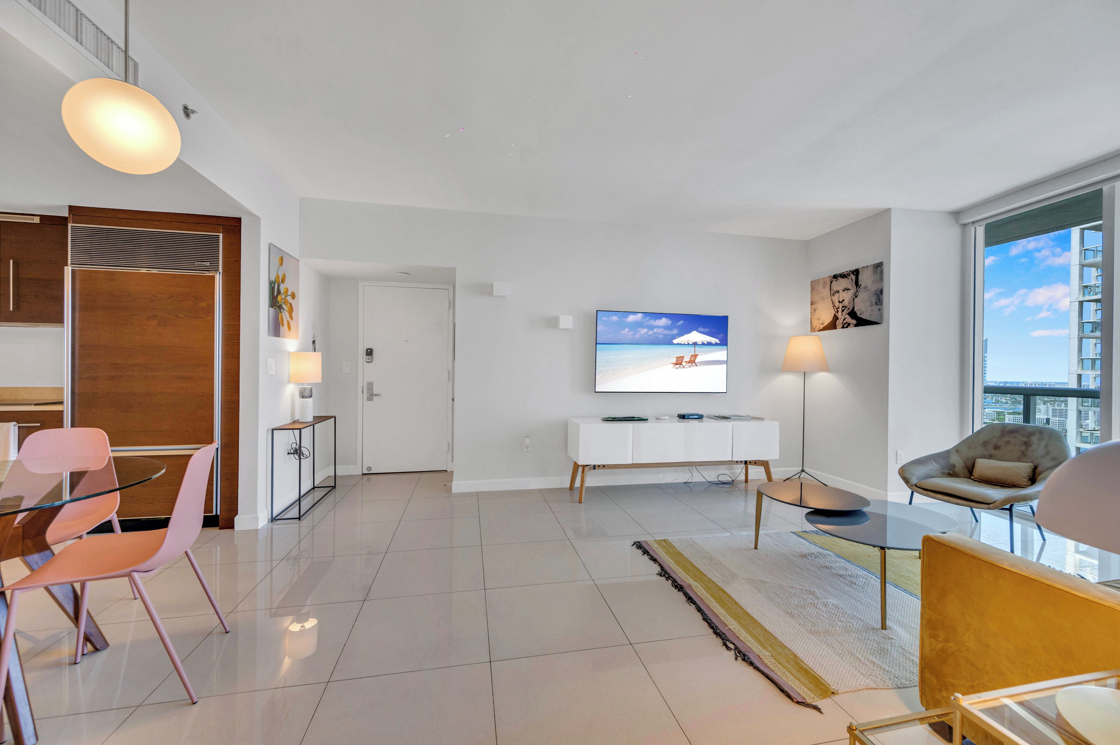 A modern living room with a TV, seating, and a view of the city.