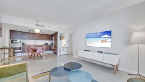 A modern living room with a flat-screen TV, a dining area, and a kitchen. - Icon Luxury 34th Floor Amazing Oceanview, Brickell (Miami)