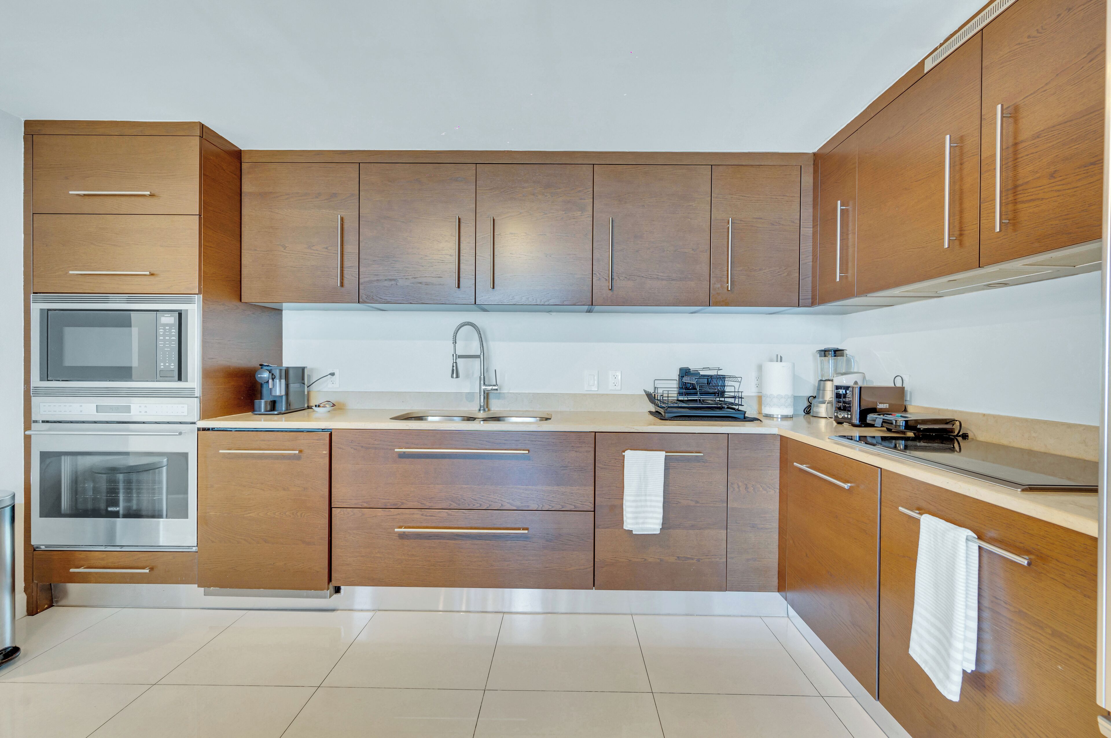 A modern kitchen with wooden cabinets, stainless steel appliances, and a central island with a sink.
