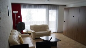 Un salon avec un canapé, une table basse, un téléviseur et un mur d’accent de couleur rouge.