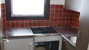 Une cuisine de taille réduite, équipée d’une cuisinière à gaz, d’un four et d’un petit évier.