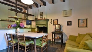 A cozy dining area with a table and chairs, a fireplace, and a green couch. - La Casa del Nonno by Interhome (Valtellina)