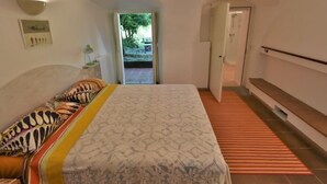 A bedroom with a bed, a nightstand, a door, and a view of the outdoors. - La Casa del Nonno by Interhome (Valtellina)