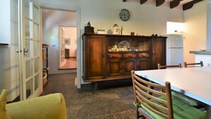 A dining area with a wooden table and chairs, a cabinet with glass doors, and a ceiling with exposed beams. - La Casa del Nonno by Interhome (Valtellina)