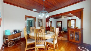 A dining room with a wooden table and chairs, a chandelier, and a wooden cabinet with glass doors.
