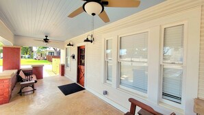A covered porch with a ceiling fan, a bench, and a small table.