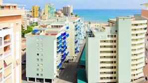 A high-rise hotel with multiple balconies, a parking area, and a view of the beach and ocean.