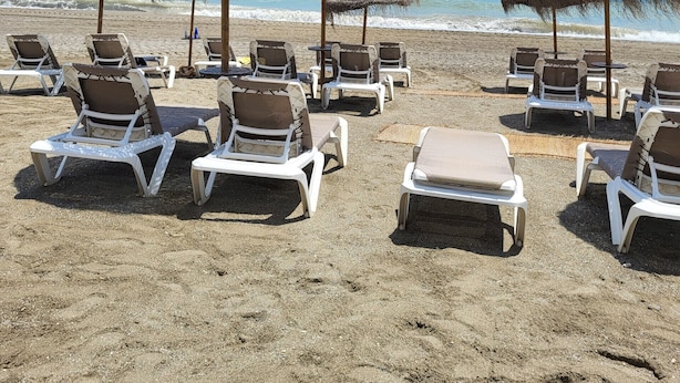 A beach with thatched umbrellas and white lounge chairs. - Beachfront 3 Bed Apt San Luis De Sabinillas (San Luis de Sabanillas)