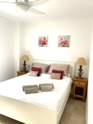 A neatly made bed with pillows, a bedside lamp, and a nightstand. - Beachfront 3 Bed Apt San Luis De Sabinillas (San Luis de Sabanillas)
