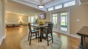 A dining area with a round table, chairs, and a chandelier. There is a sofa and a window with a view of the outdoors. - Waterfront Georgetown Retreat on Lake George! (Georgetown)