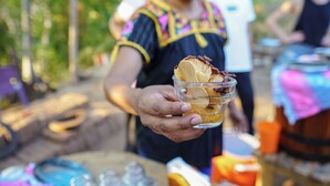 A person holding a glass with a dessert.