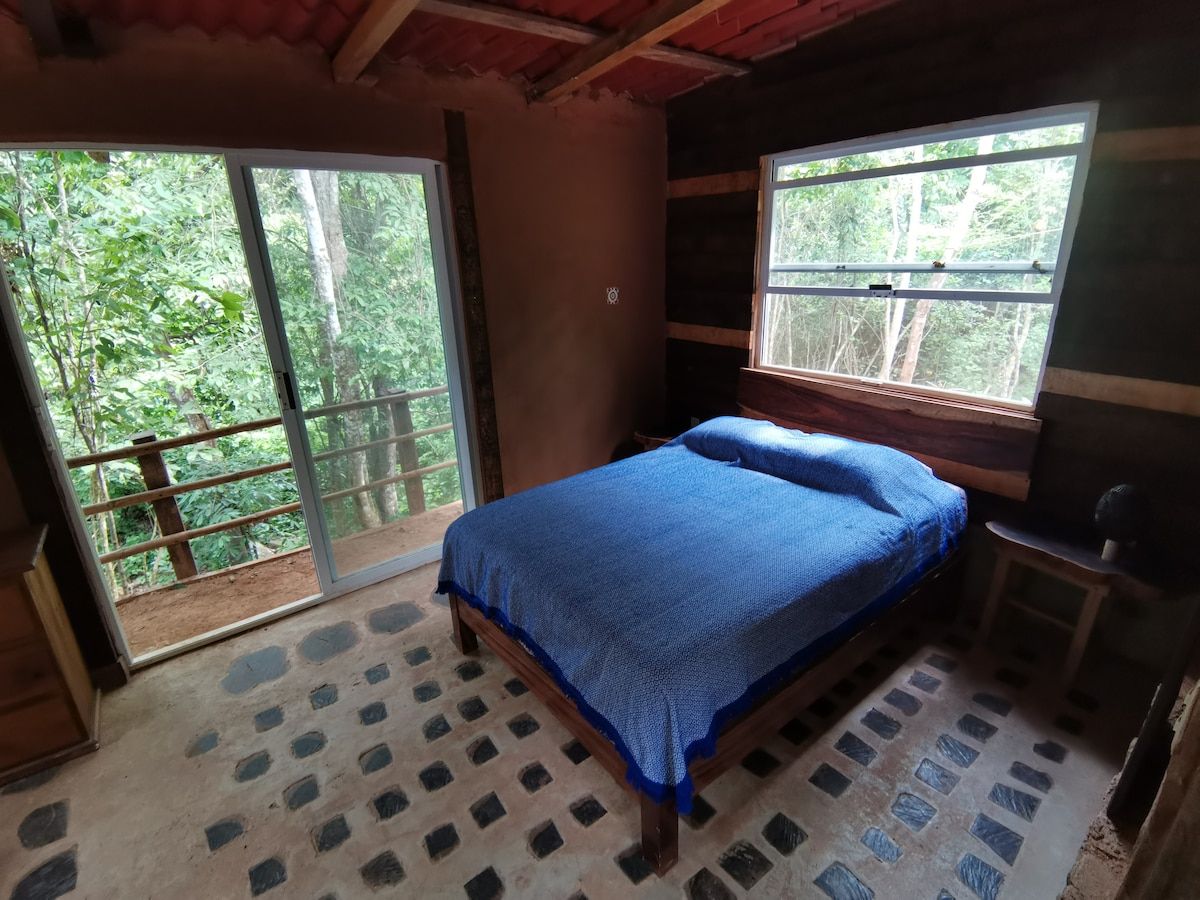 Une chambre à coucher avec un lit, une fenêtre et une vue sur la verdure.