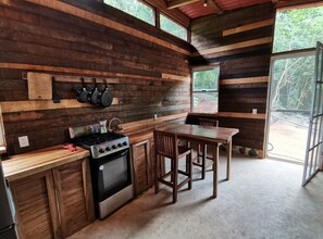 A rustic kitchen with wooden walls, a gas stove, and a dining table.