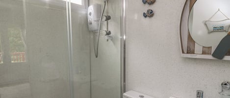 A modern bathroom with a glass-enclosed shower, a white sink, and decorative fish wall art.