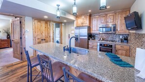 A modern kitchen with granite countertops, stainless steel appliances, wooden cabinets, and a bar area with stools. - Labor Day Sale - Limited Time Offer, Save up to 30% (Park City)