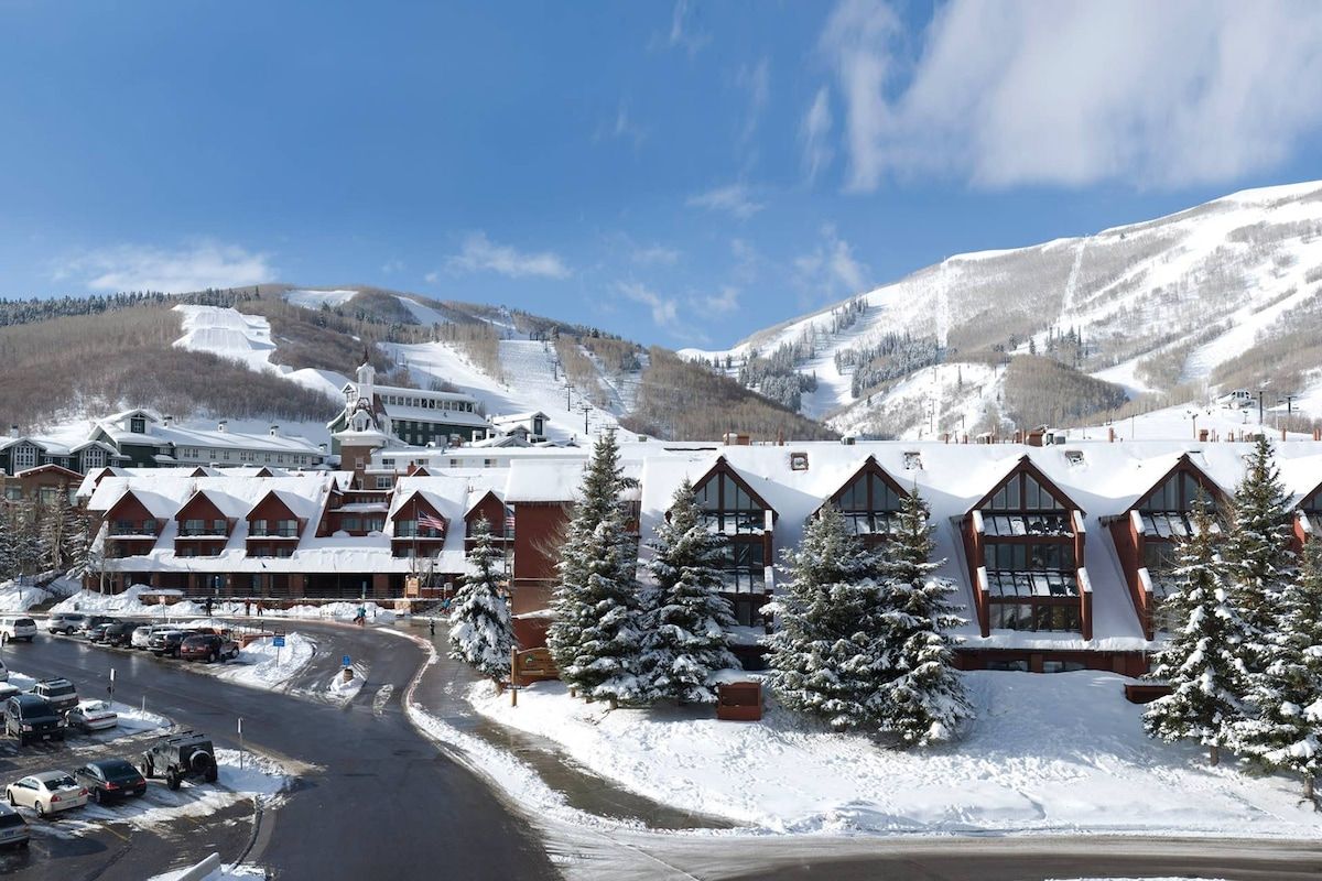 Eine Lodge mit Skipiste im Hintergrund, umgeben von schneebedeckten Bäumen.