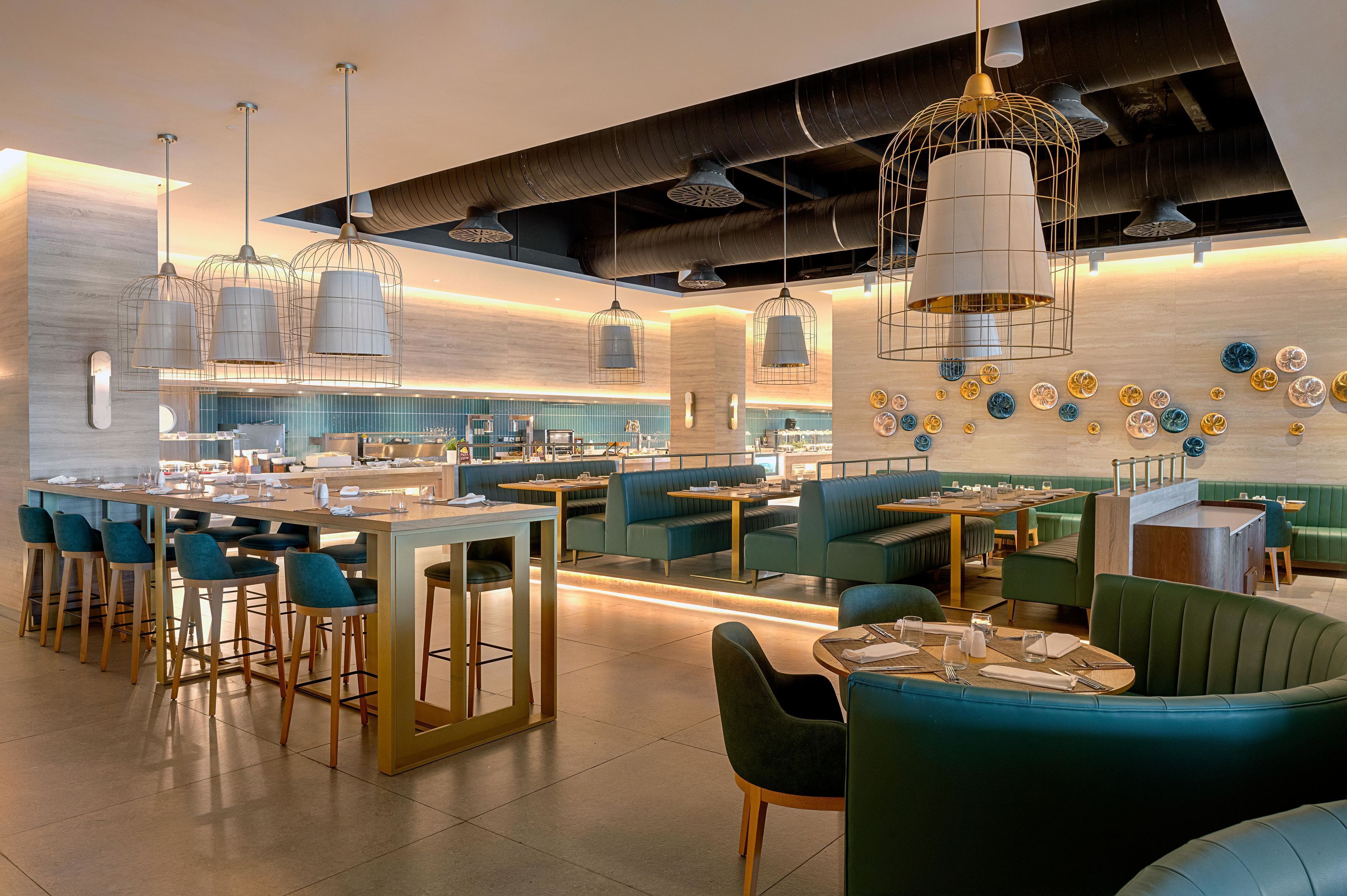 Un interno ristorante moderno con posti a sedere al bancone, cabine e cucina sullo sfondo.