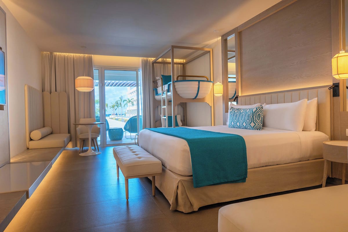 Ein modernes Hotelzimmer mit einem großen Bett, einer Sitzecke und Blick ins Freie.