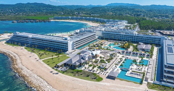 Ein Resort mit mehreren Gebäuden, einem großen Poolbereich und einem Strand.