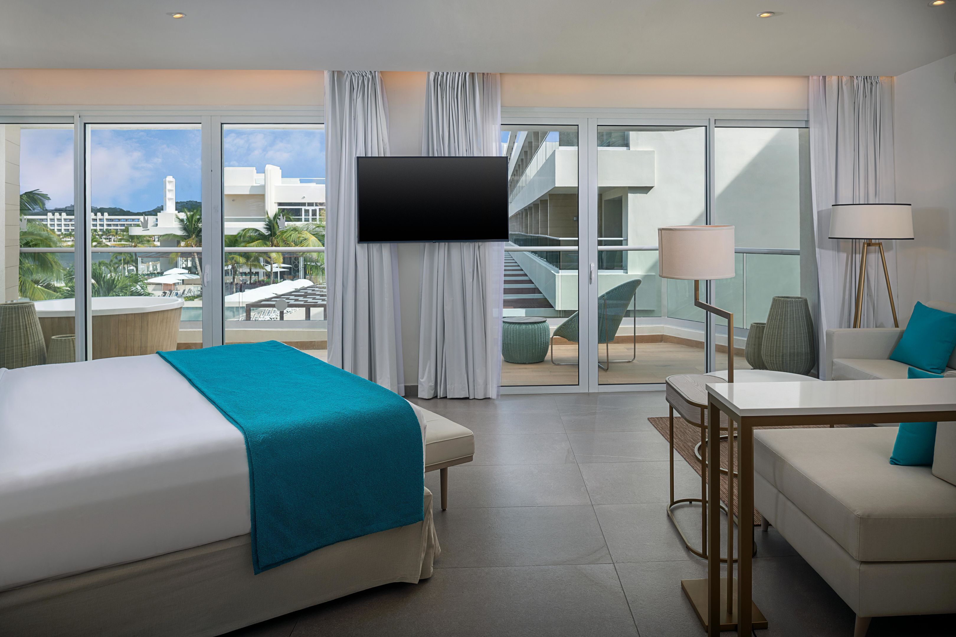 Une chambre d’hôtel équipée d’un lit, d’un bureau, d’une chaise, d’une télévision et offrant une vue sur le complexe hôtelier.