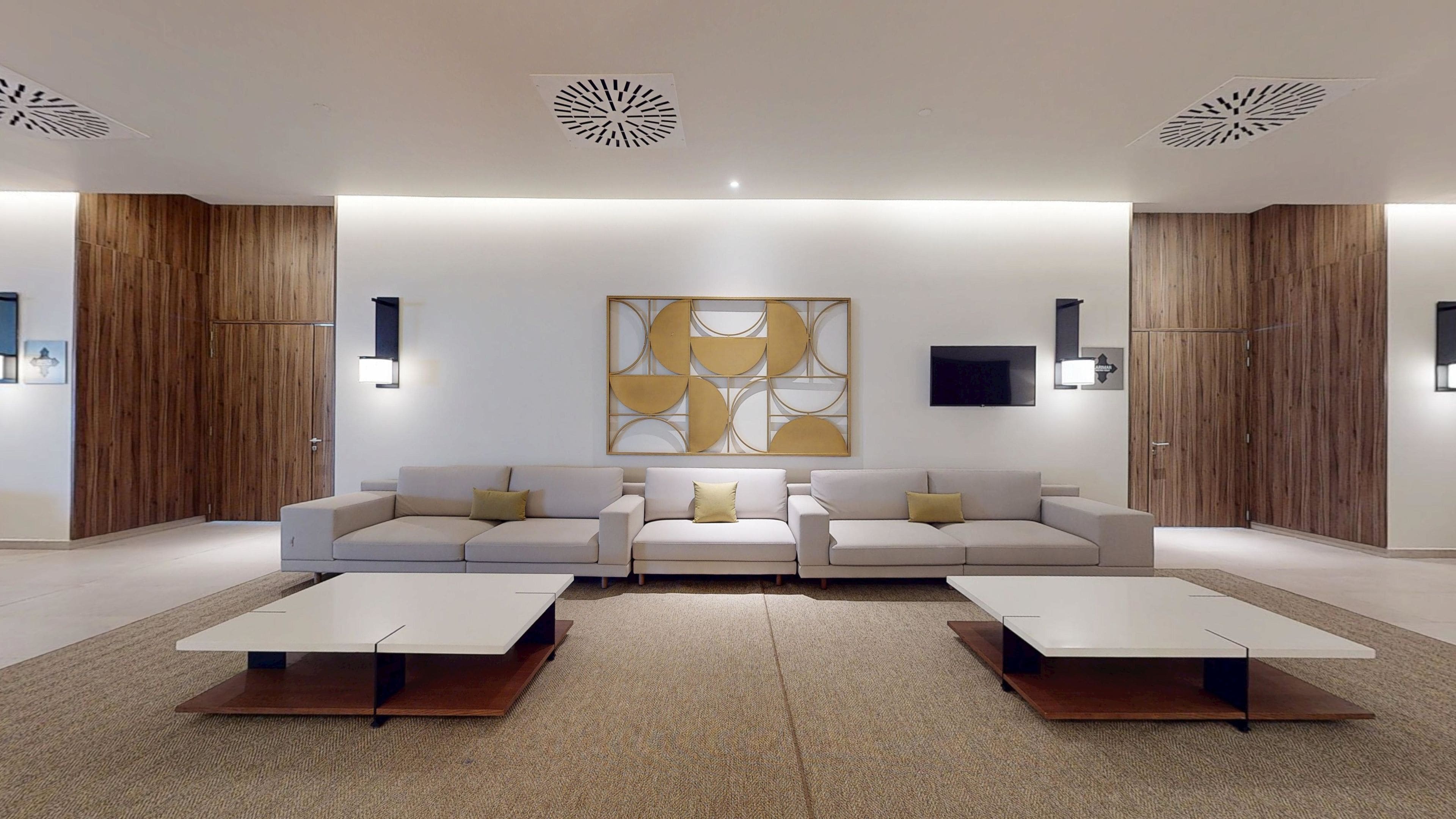 Un soggiorno moderno con un divano componibile, due tavolini, una grande opera d'arte astratta e armadi a muro in legno.