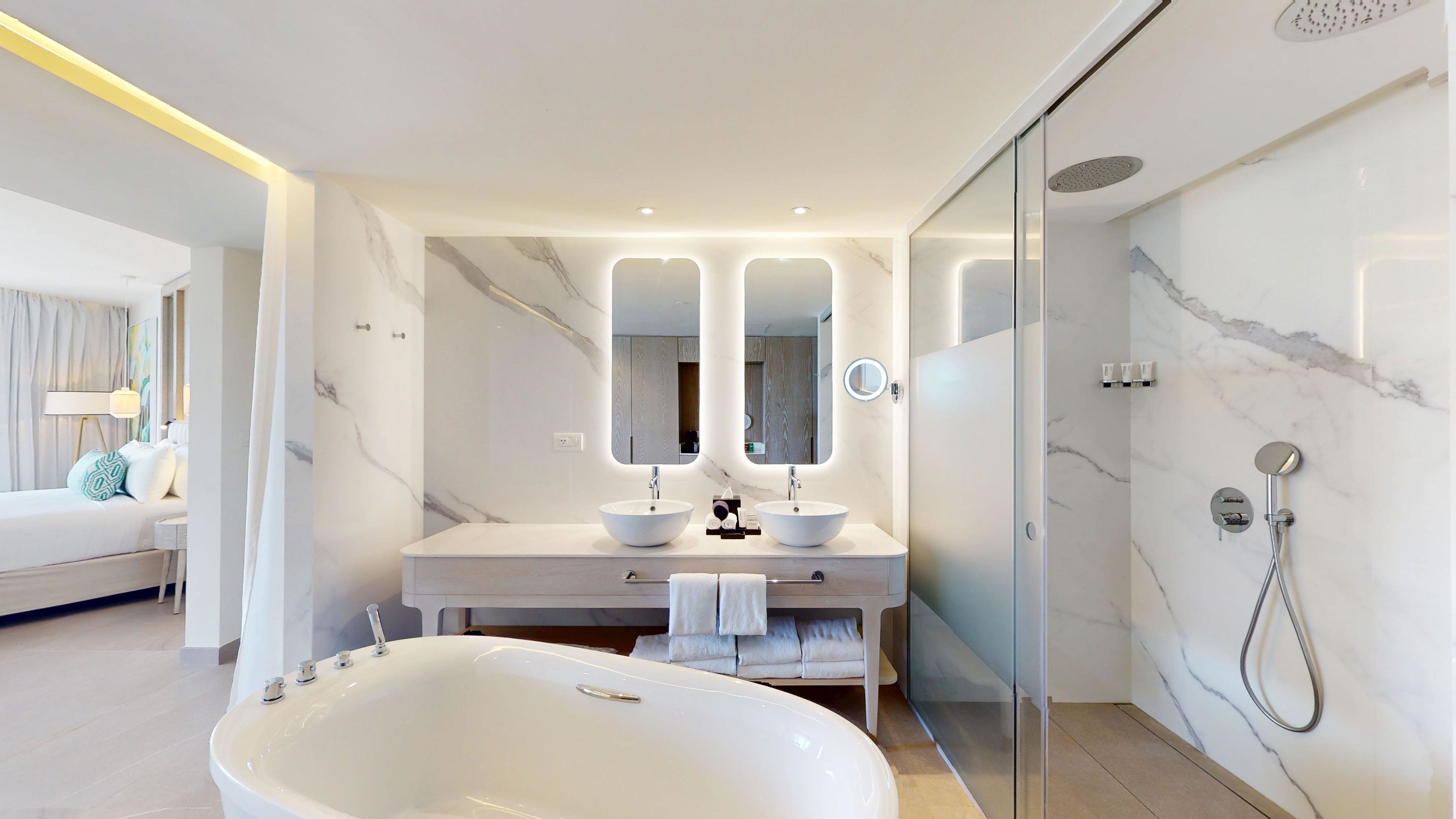 Un baño moderno con una bañera grande, dos lavamanos y una ducha con mampara de vidrio.