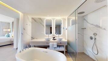 Un baño moderno con una bañera grande, dos lavamanos y una ducha con mampara de vidrio.