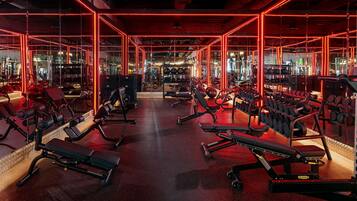 A gym with various exercise equipment, including benches, dumbbells, and weight machines.
