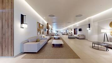 A modern hotel lobby with a long corridor, sofas, and a coffee table.