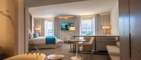 Una habitación de hotel con cama, televisión, escritorio, silla, sofá y bañera.