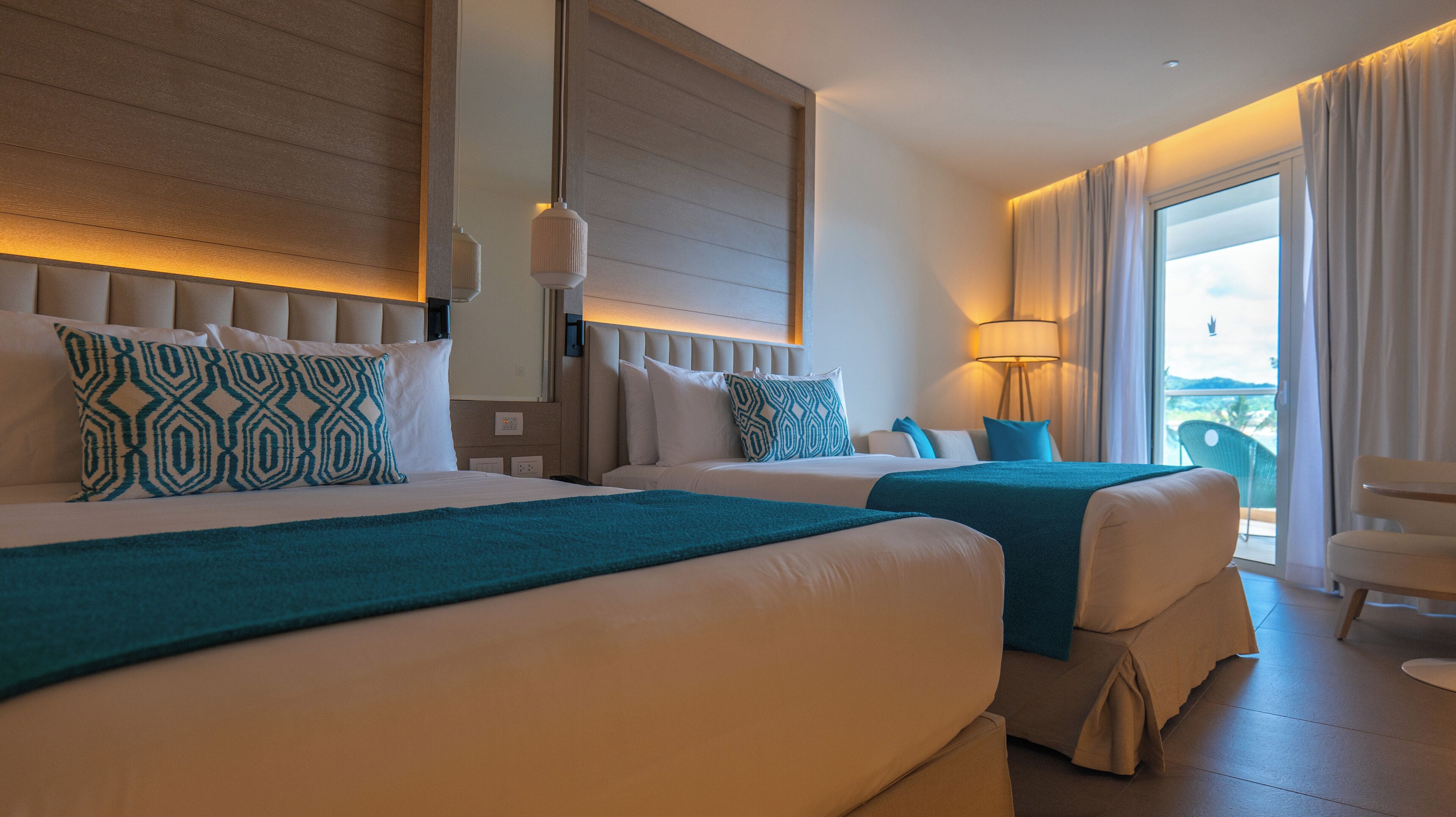 Une chambre d’hôtel avec deux lits, une grande fenêtre et un balcon.