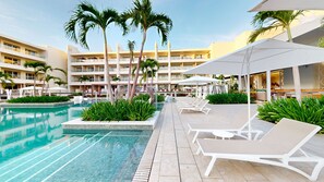 A pool area with lounge chairs, palm trees, and a multi-story hotel building in the background.