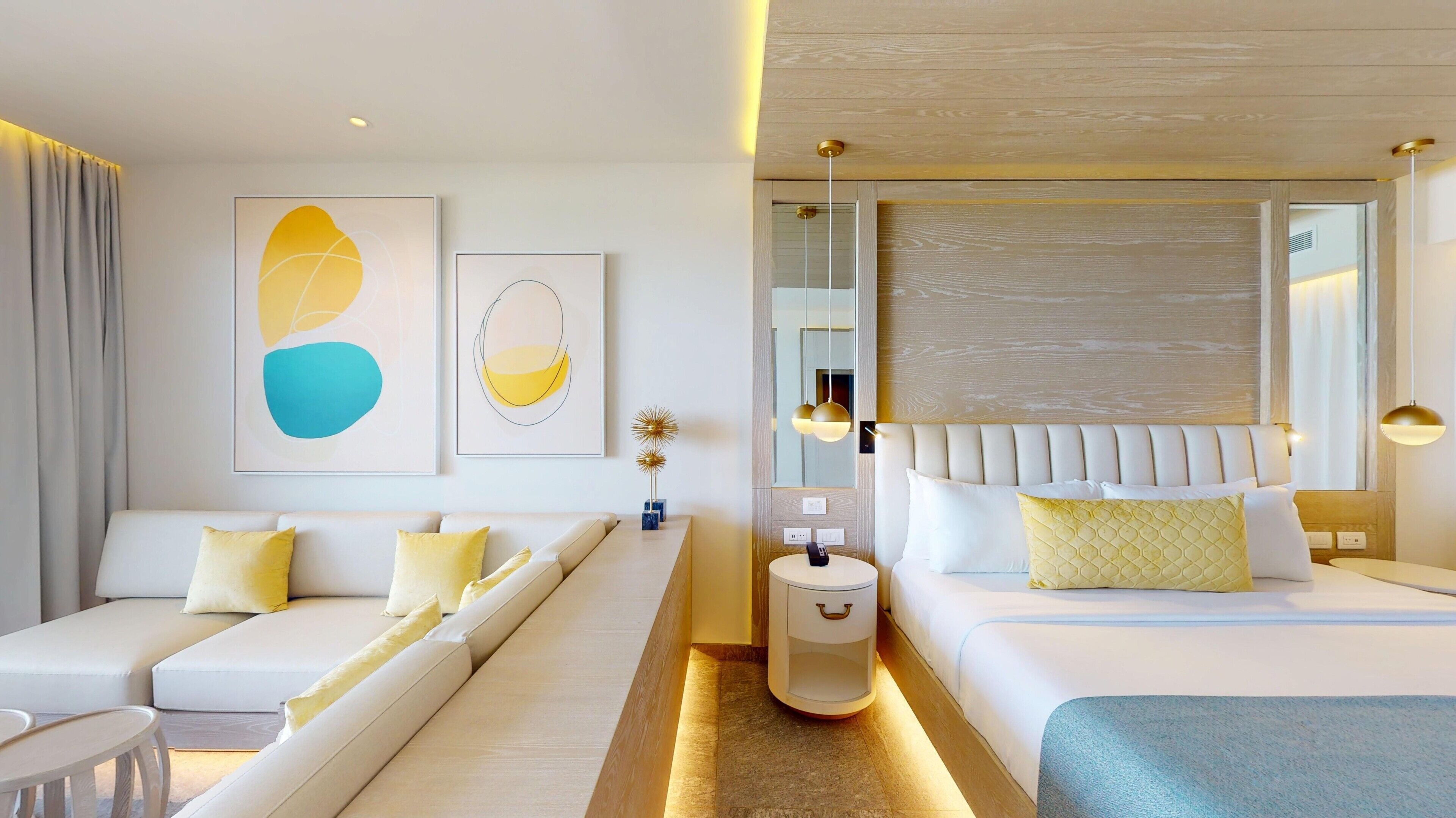 Habitació d'hotel moderna amb un sofà, un llit, una taula de nit i obra d'art a les parets.