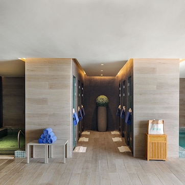 A modern spa area with a pool, a massage table, and a reception desk.