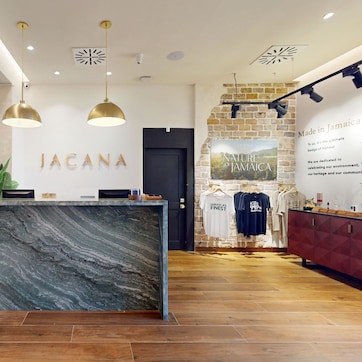 A reception area with a marble counter, potted plants, and a sign reading "JACANA".