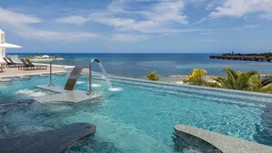 An infinity pool with a water feature, lounge chairs, and a view of the ocean. - Princess Senses The Mangrove Resort - Adults Only  (Green Island)