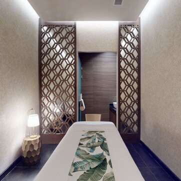 A narrow hallway with a long table in the center, flanked by two wooden partitions with a geometric pattern.