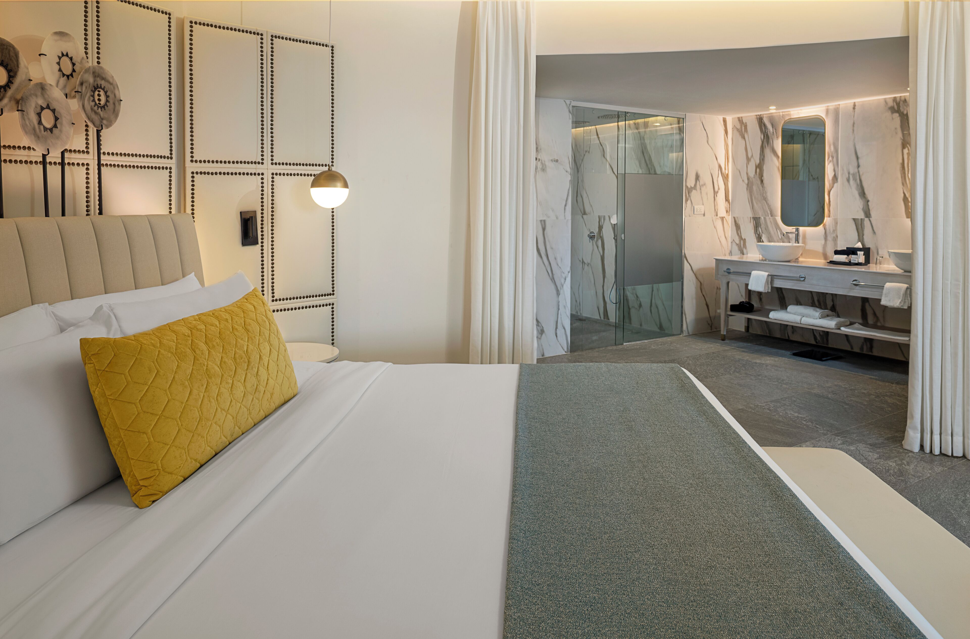 A hotel room with a bed, a bathroom with a marble vanity, and a shower.