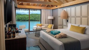 A hotel room with a bed, a desk with a TV, a table with a chair, and a view of the outdoors. - Princess Senses The Mangrove Resort - Adults Only  (Green Island)