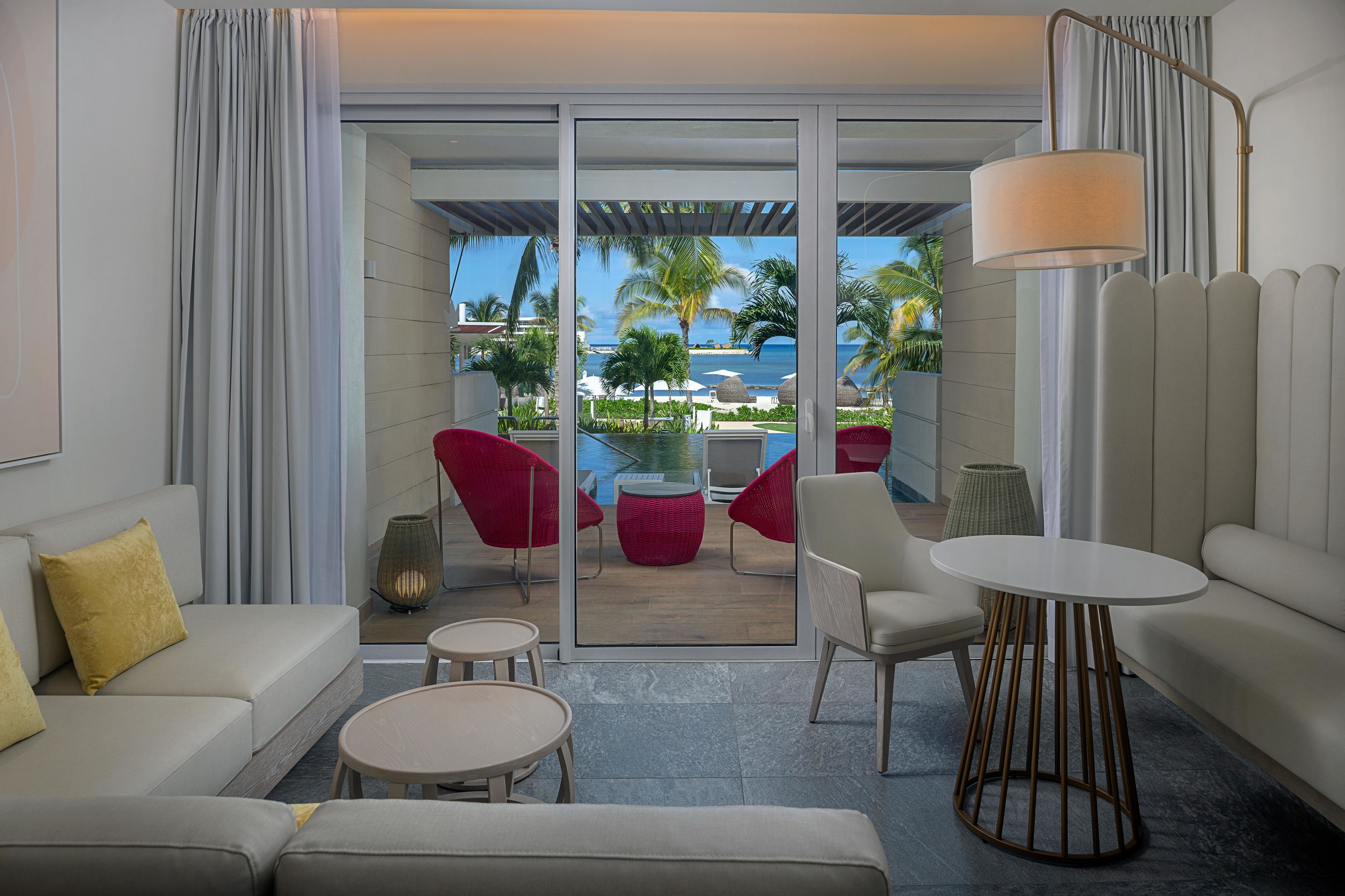 Una habitación de hotel moderna con un balcón, un sofá, una mesa y una lámpara.