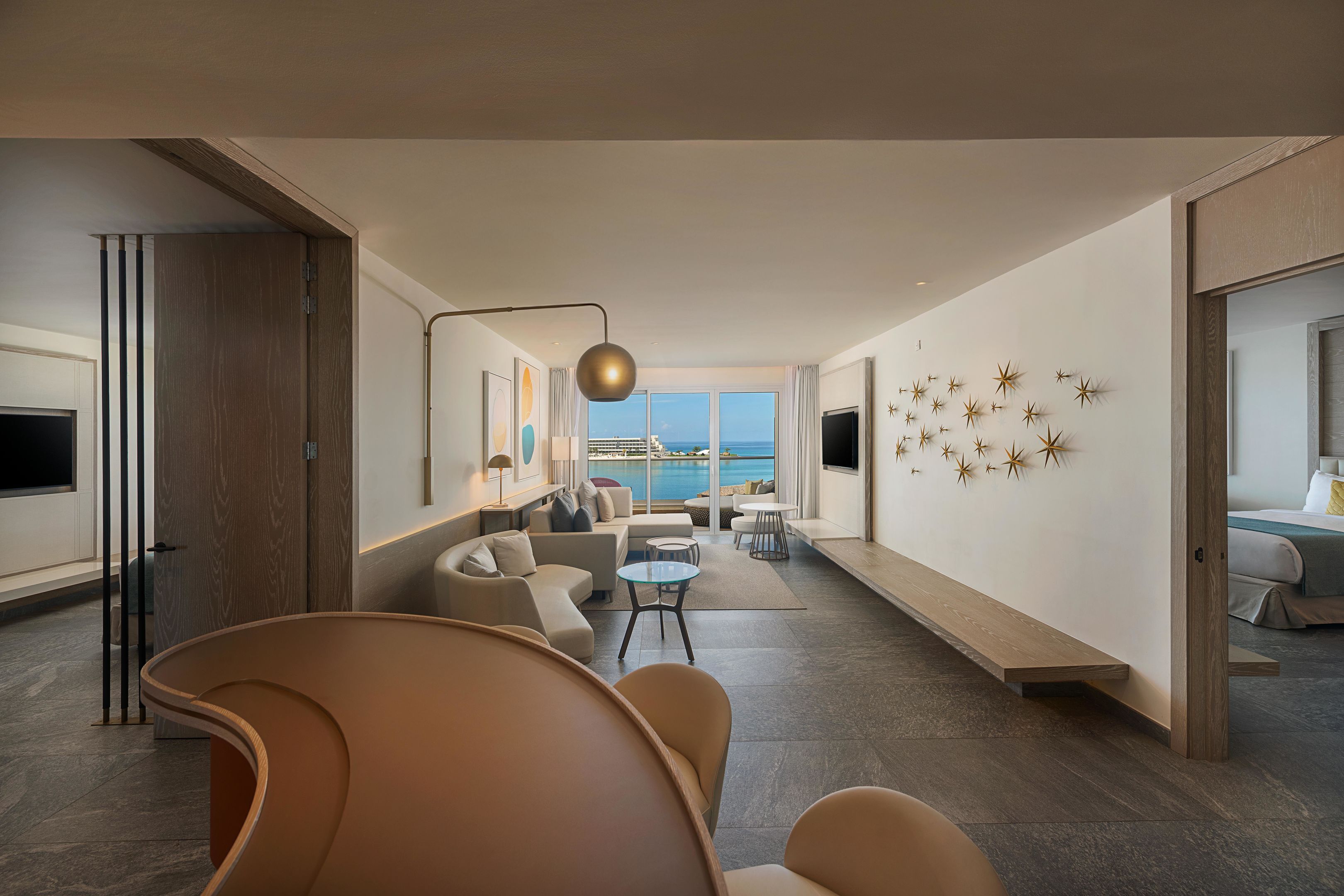 A modern living room with a sofa, a coffee table, and a view of the sea.