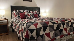 A neatly made bed with a geometric patterned bedspread, two bedside lamps, and a framed picture on the wall. - Vacation Condo #2 2BR with full kitchen, walk to river and shops, pets welcome (Hardy)