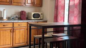 A kitchen with wooden cabinets, a microwave, a coffee maker, and a table with chairs. - Vacation Condo #2 2BR with full kitchen, walk to river and shops, pets welcome (Hardy)